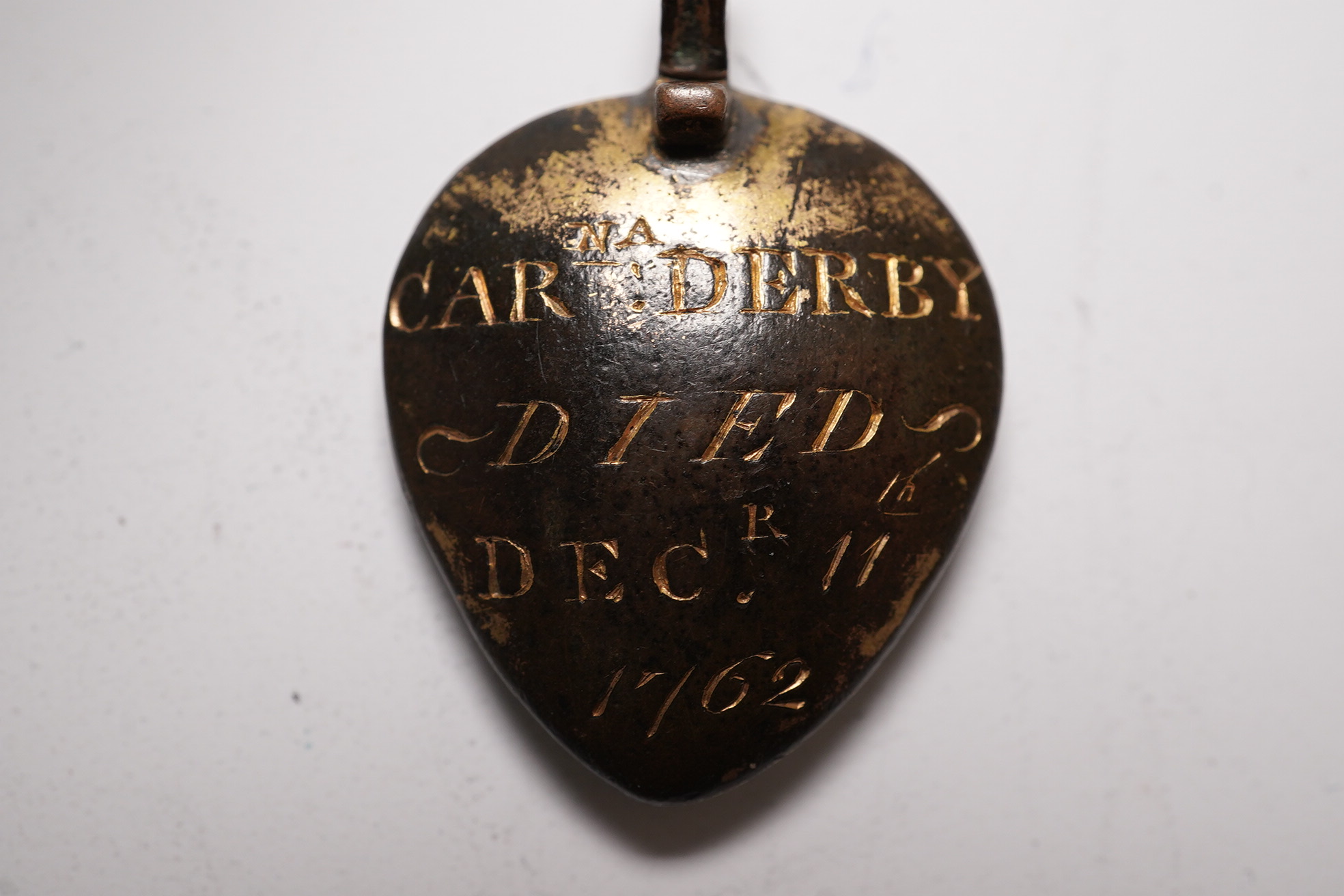 An 18th century gilt metal heart shaped mourning pendant, with engraved inscription, 'CARna DERBY DIED DEC 11th, 1762' and plaited hair beneath a glazed panel verso, 27mm.